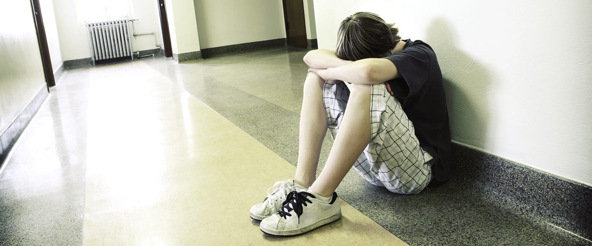 Sad young man sitting against a wall